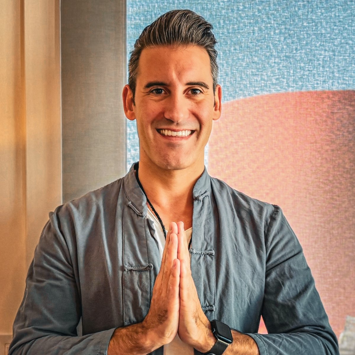 Joel smiling with his palms pressed together in greeting