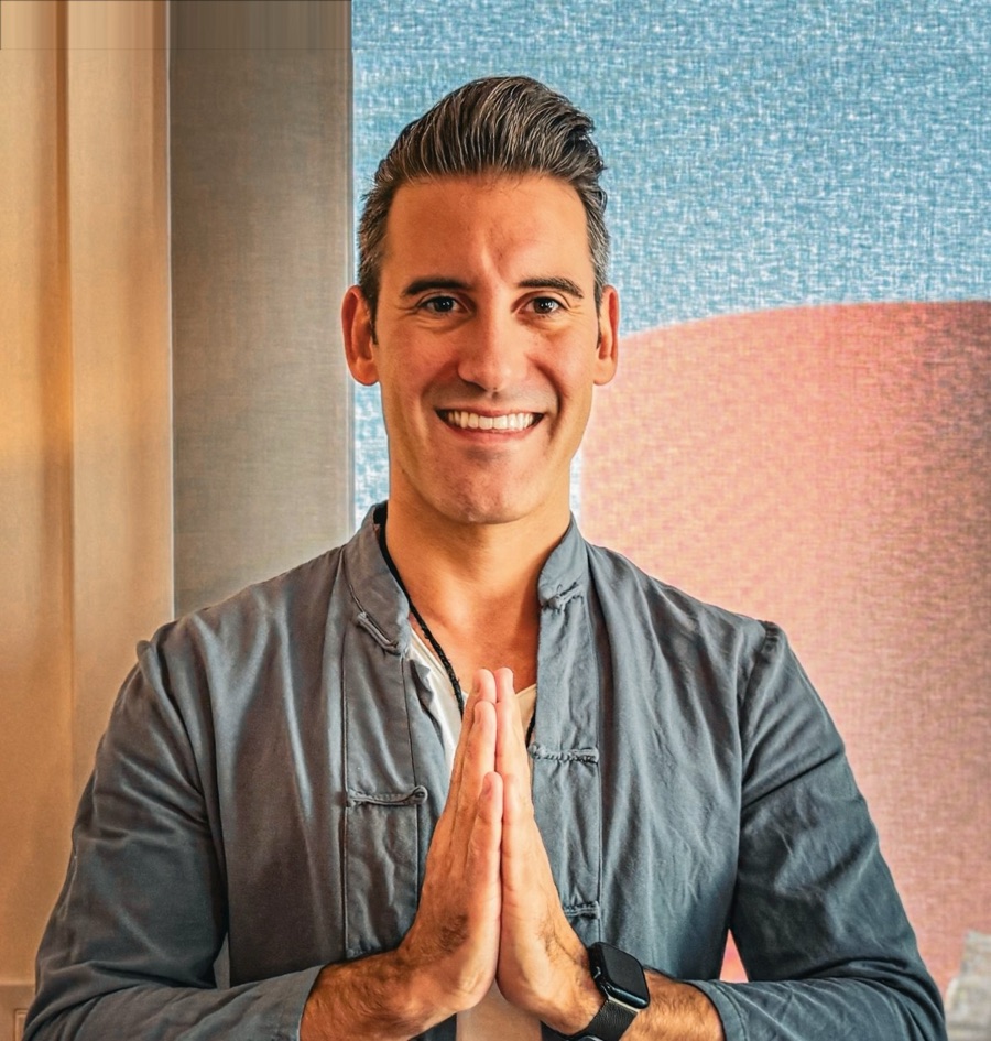 Joel smiling with his palms pressed together in greeting